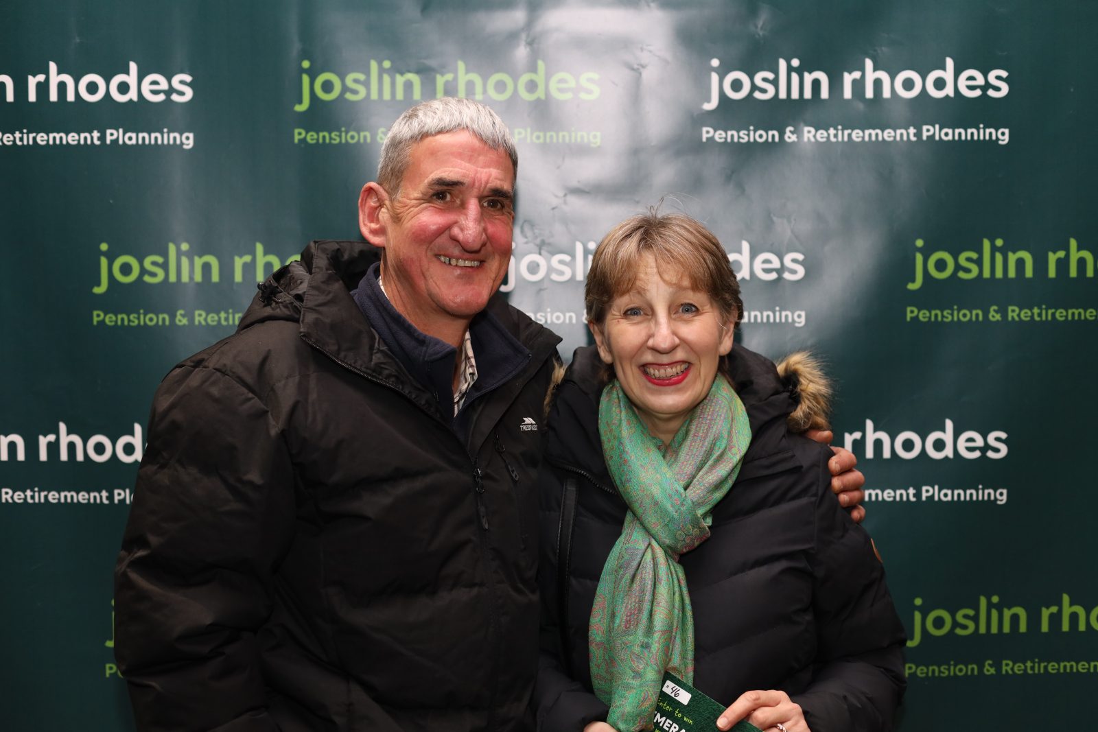 Joslin Rhodes - Happy Joslin Rhodes clients smiling in front of a branded Joslin Rhodes banner.