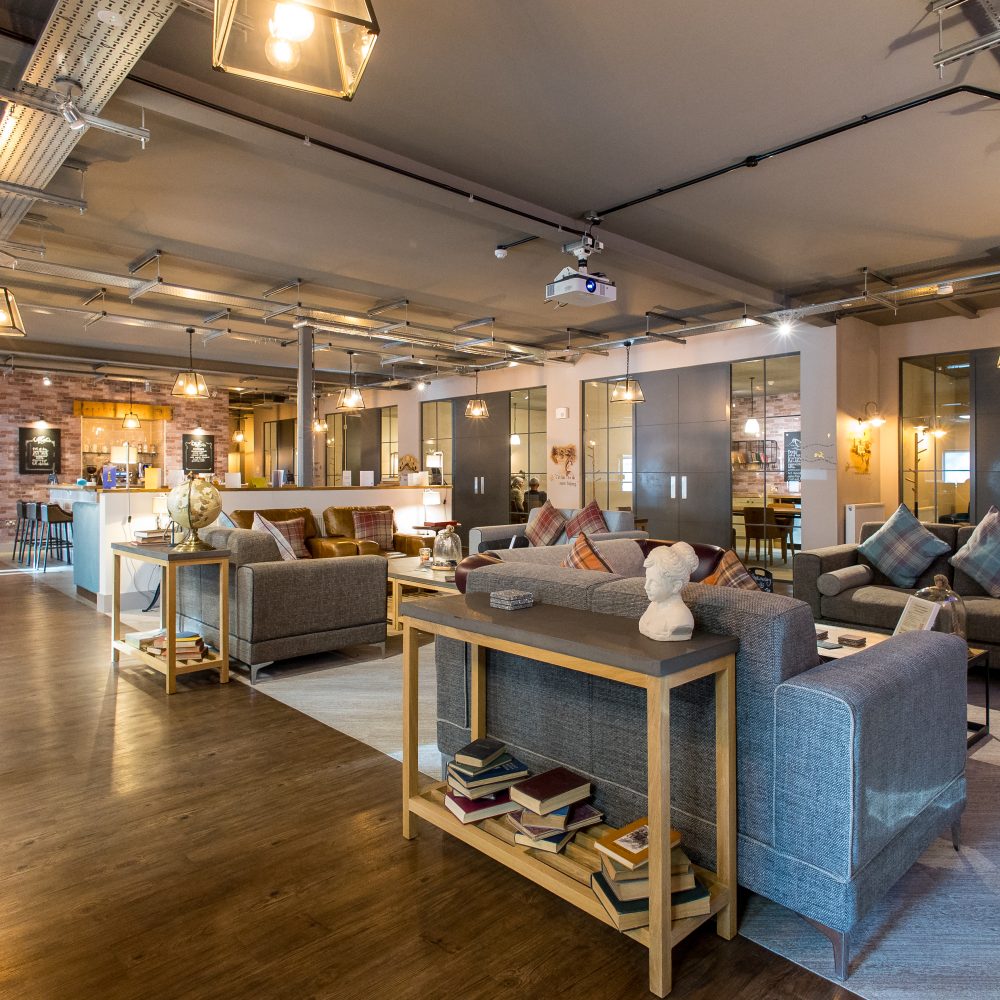 Joslin Rhodes - Interior of the Joslin Rhodes office featuring a cosy lounge area, bistro, and kitchen, with warm lighting and comfortable sofas creating a welcoming atmosphere.