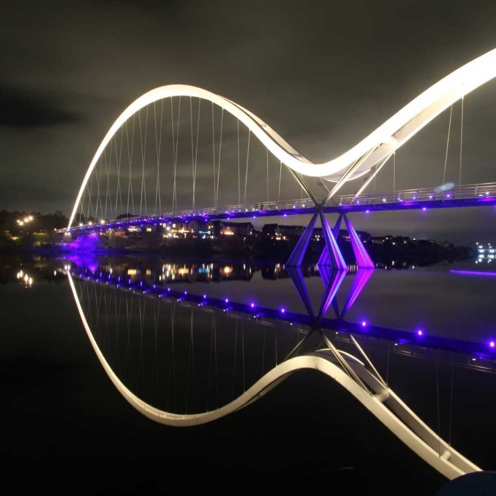 Joslin Rhodes - Stockton Infinity Bridge illuminated at night against a dark sky.