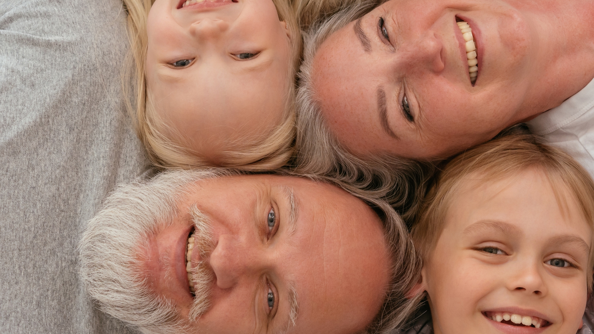 Joslin Rhodes – Smiling grandparents lying down with their grandchildren, all looking happy and relaxed together.
