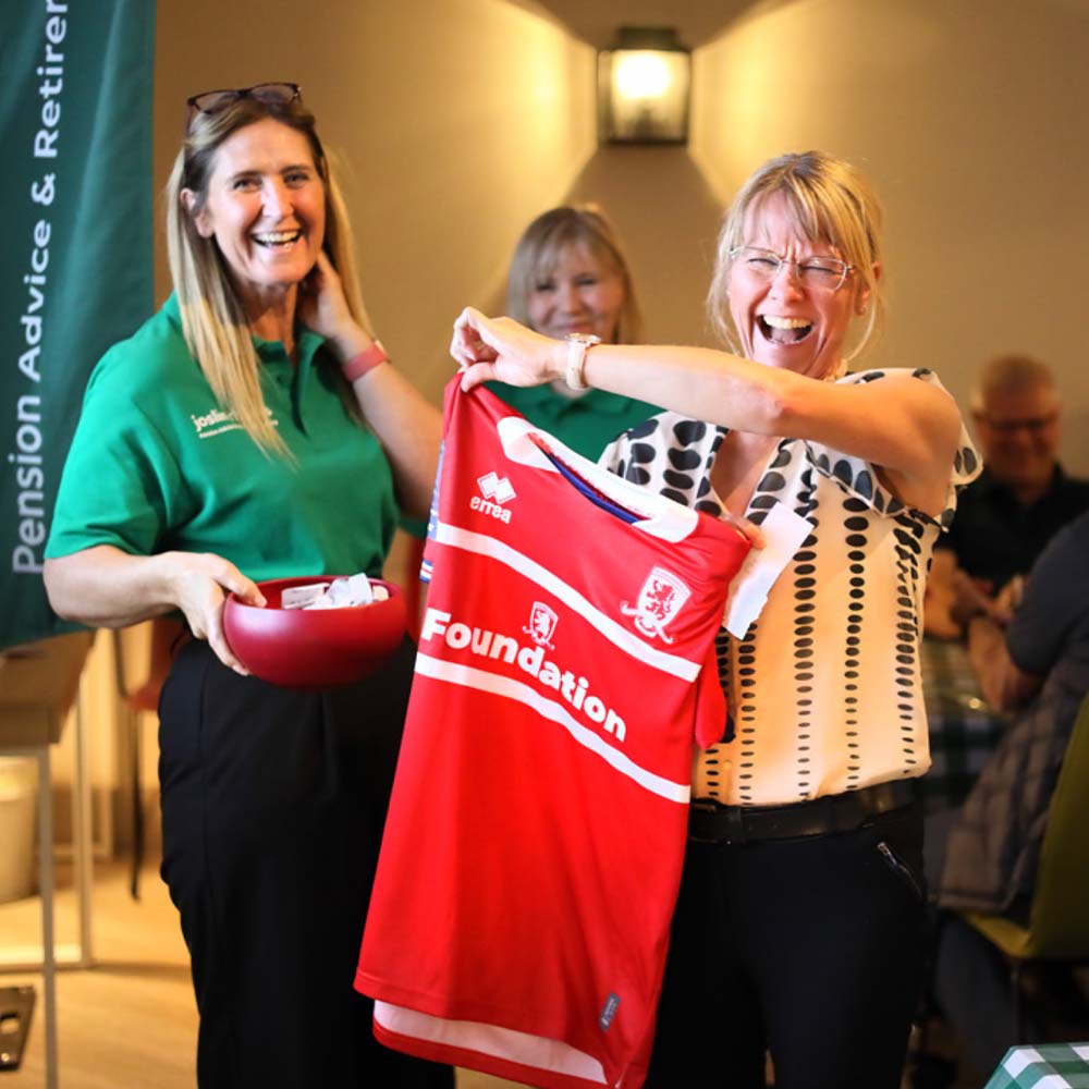 Joslin Rhodes client laughing with joy after winning a prize - a Middlesbrough FC (Boro) shirt.