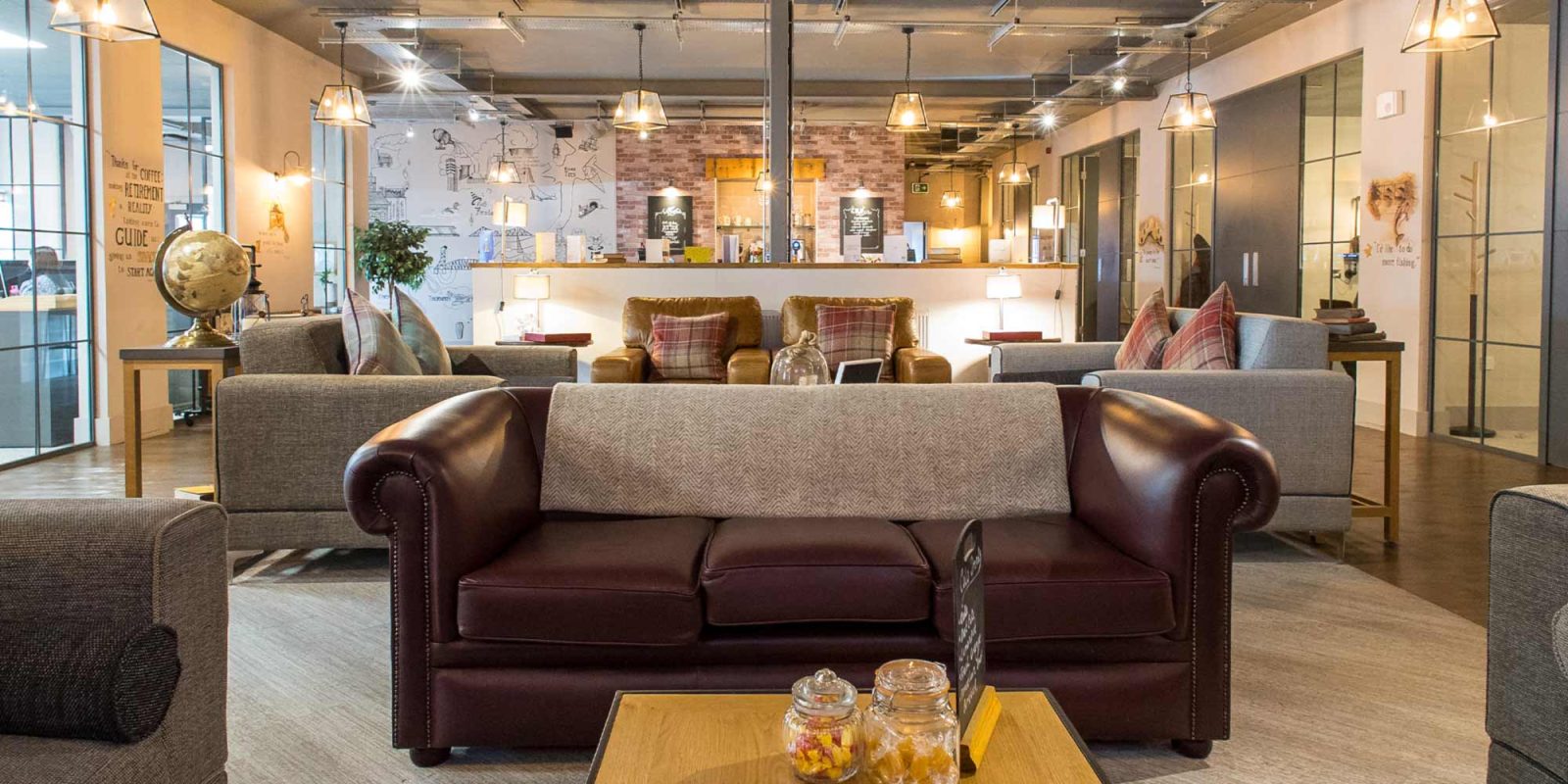 Interior of the Joslin Rhodes office featuring a cosy lounge area, bistro, and kitchen, with warm lighting and comfortable sofas creating a welcoming atmosphere.