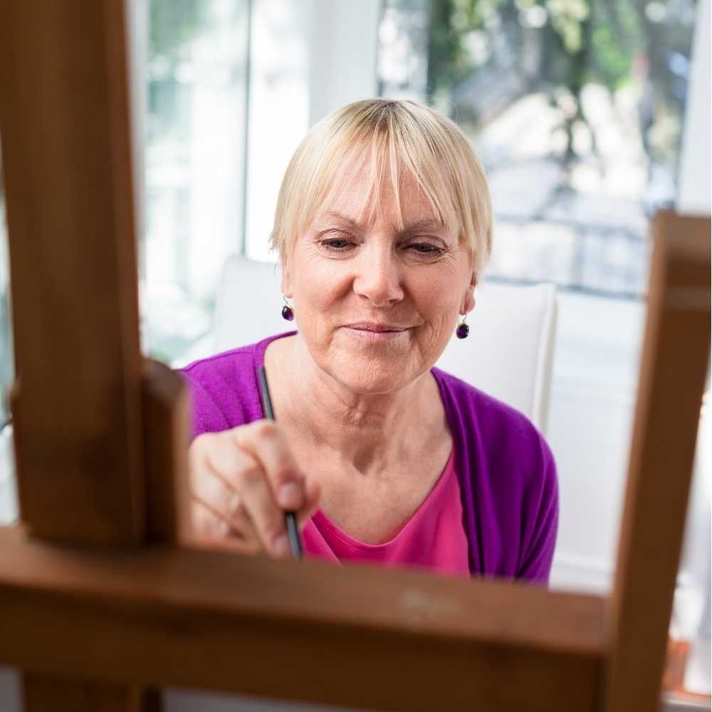 Joslin Rhodes - Woman painting inside her home, enjoying a retirement hobby.